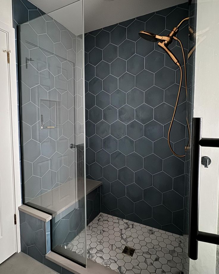 a bathroom with hexagonal tiles on the wall and floor, including a walk in shower