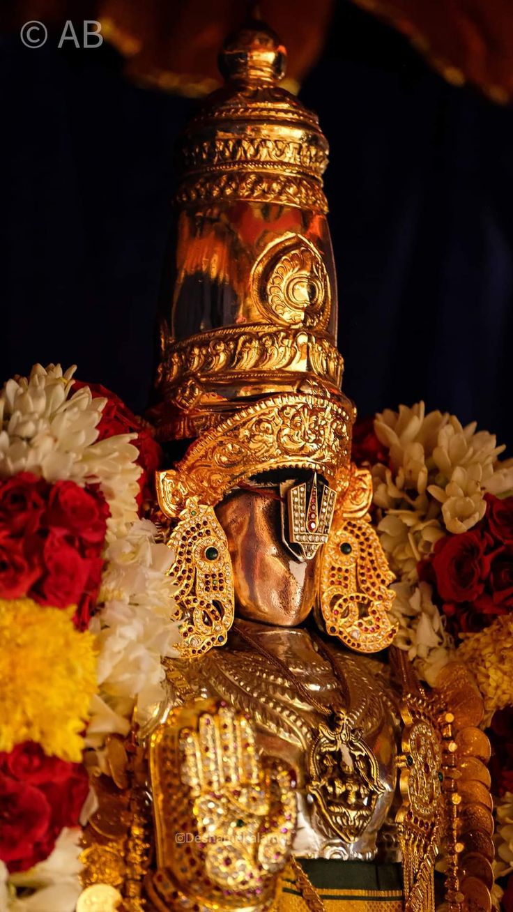 an elaborately decorated golden statue with flowers in the background