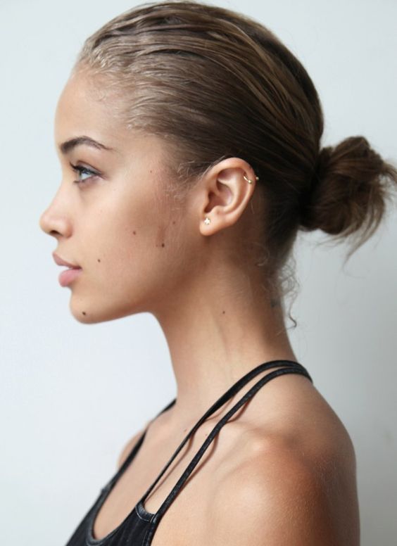 a young woman with her hair in a pony tail style, looking off to the side