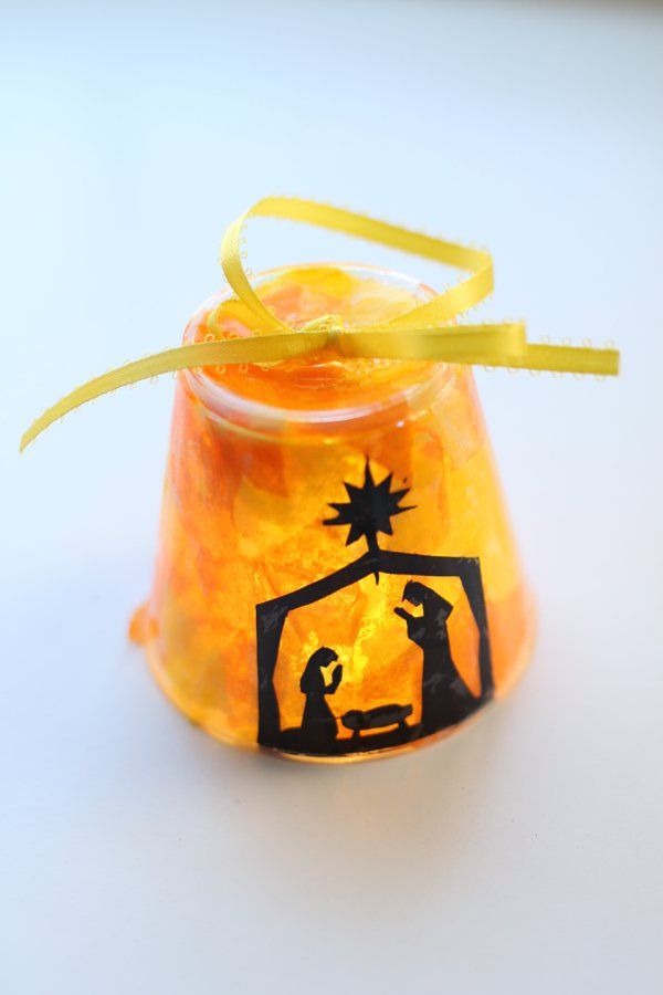 a small glass jar filled with candy and a nativity scene on it's lid