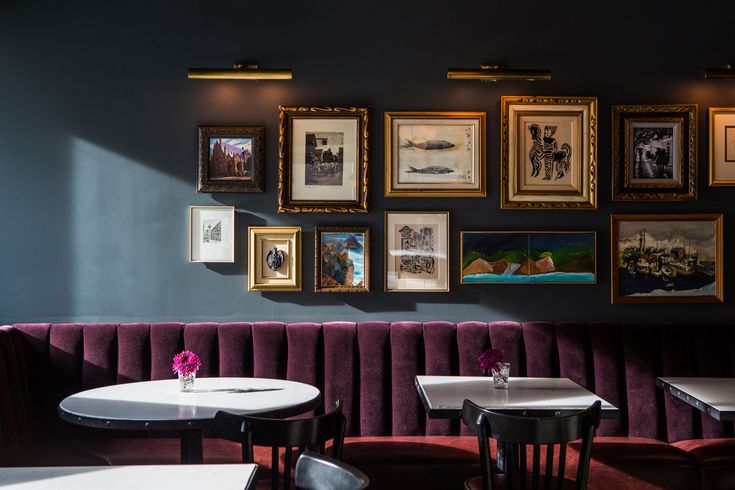 an empty restaurant with tables and chairs in front of pictures on the wall above them