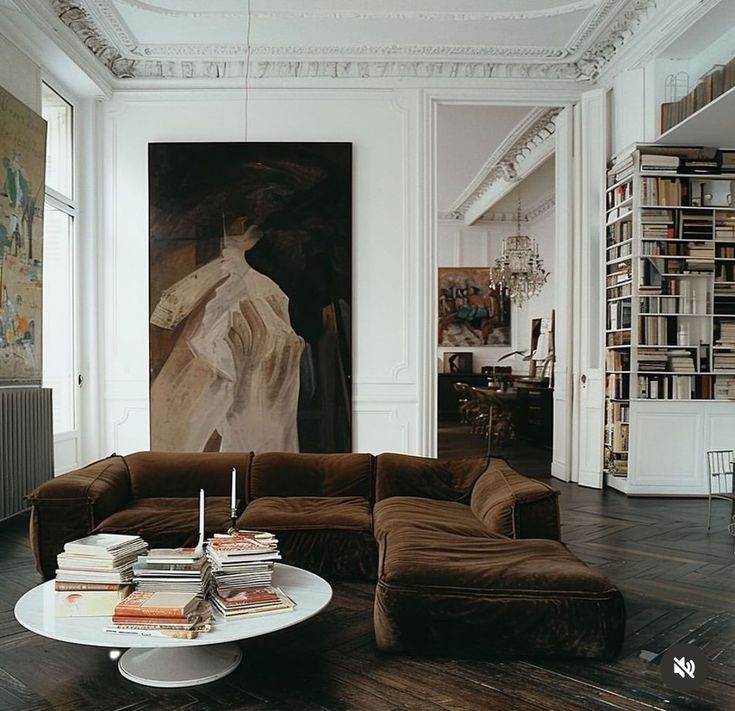 a living room filled with lots of furniture and books on top of a hard wood floor