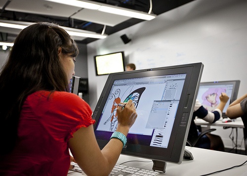 a woman sitting in front of a computer screen