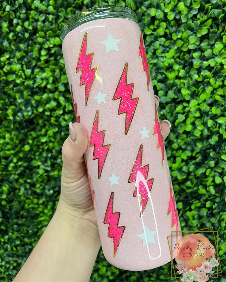 a hand holding a pink tumbler cup with stars and lightnings on the side