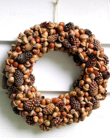 a wreath made out of pine cones and acorns is hanging on the door