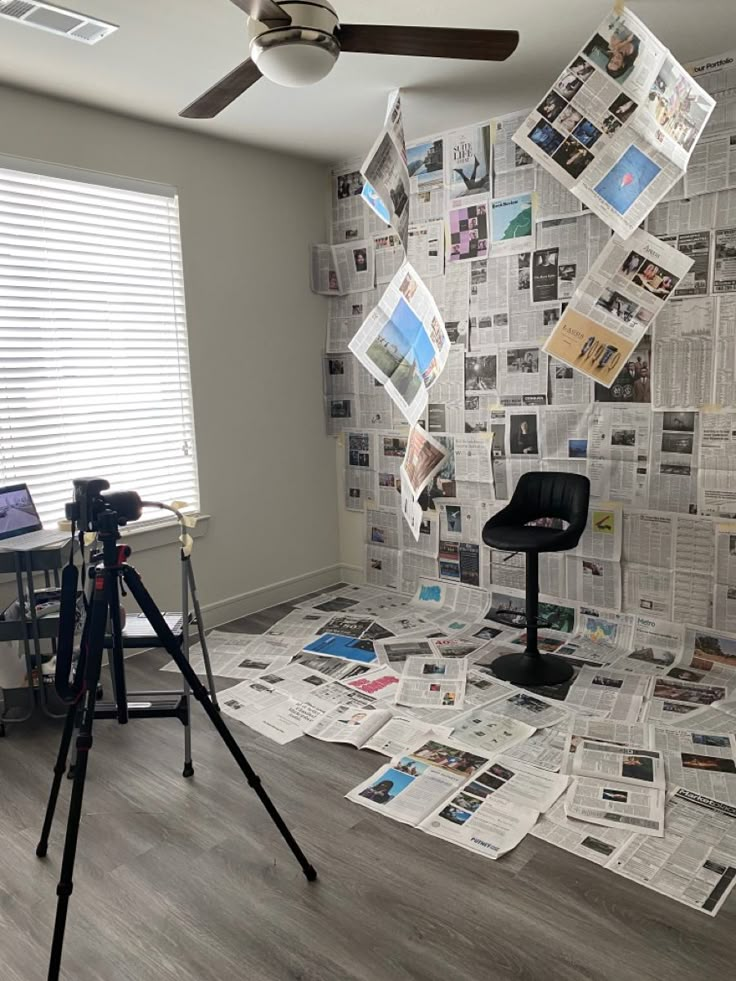 a room that has newspapers all over the floor and on the wall, as well as a ceiling fan