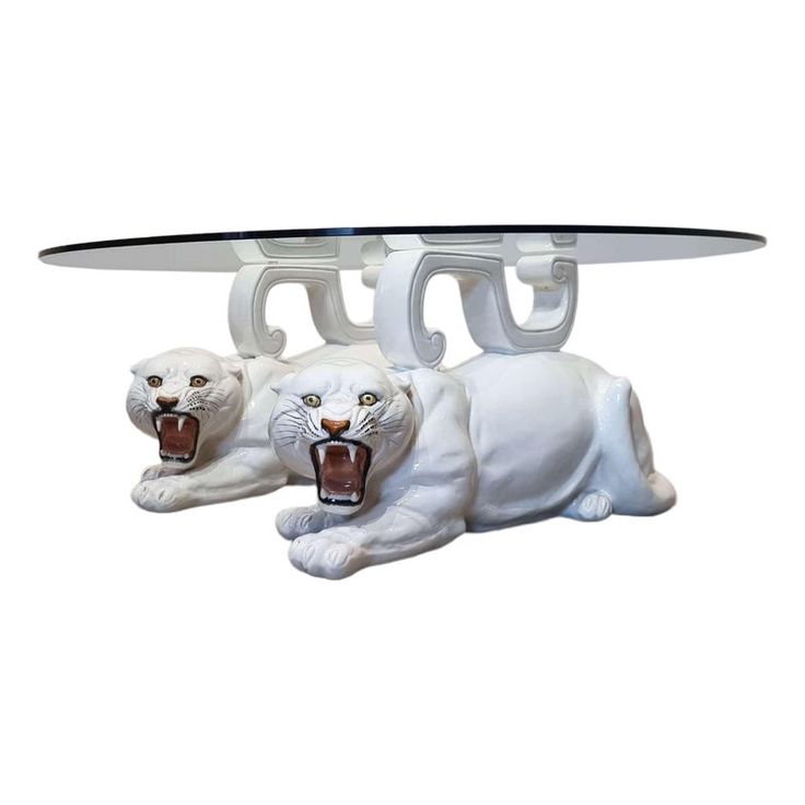 two white tiger figurines sitting under a glass table