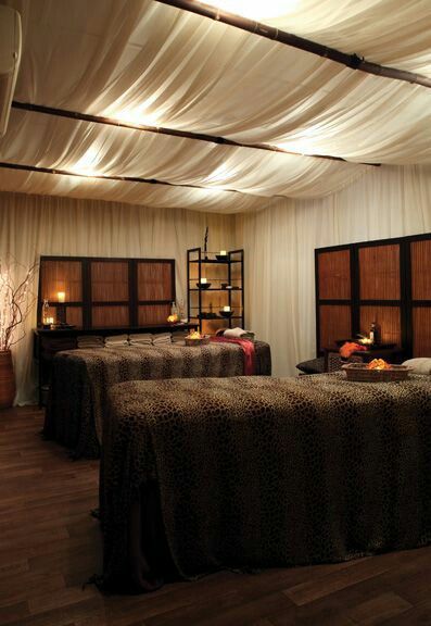 two beds in a room with white drapes on the ceiling