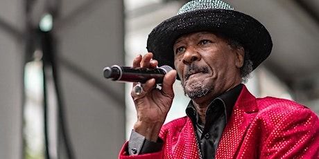 a man in a red jacket and black hat holding a microphone