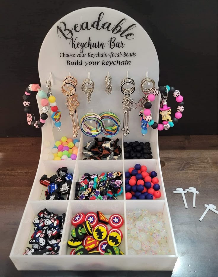 a white display case filled with lots of different earrings and jewelry on top of a wooden table