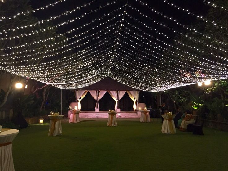 an outdoor wedding venue with white lights on the ceiling and tables set up for dinner