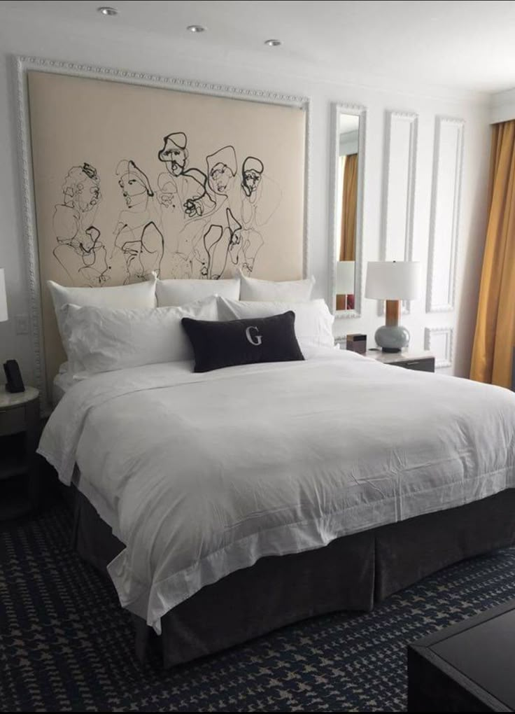 a large bed sitting in a bedroom next to a wall mounted art above the headboard