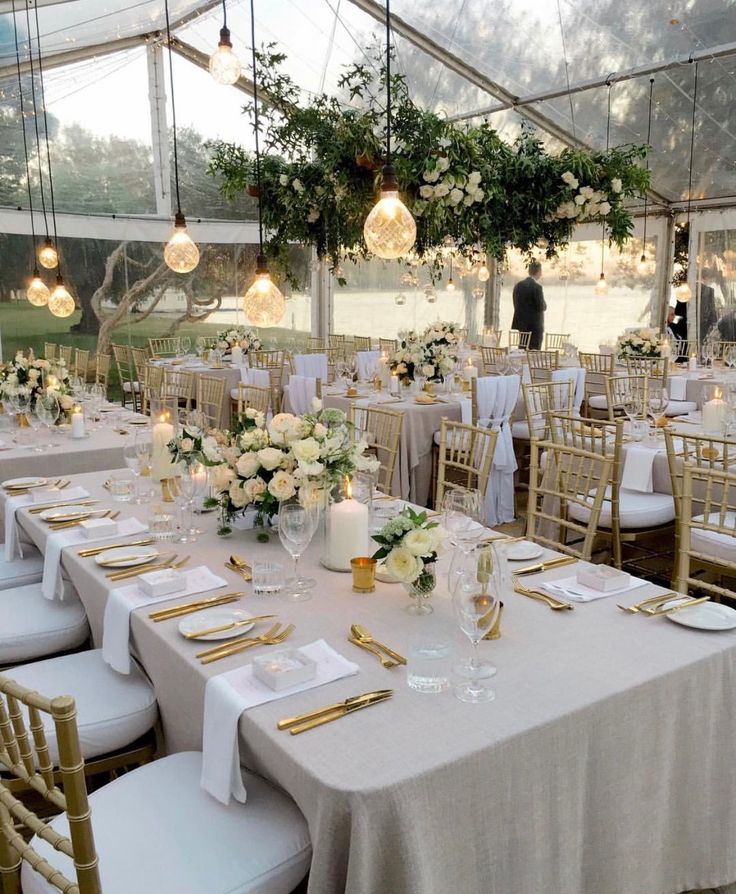 tables set up for an event with white linens and gold place settings