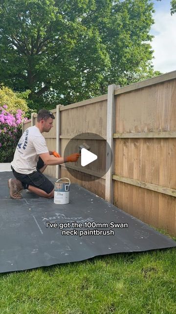 a man is painting the side of a fence with a paint can and buckets