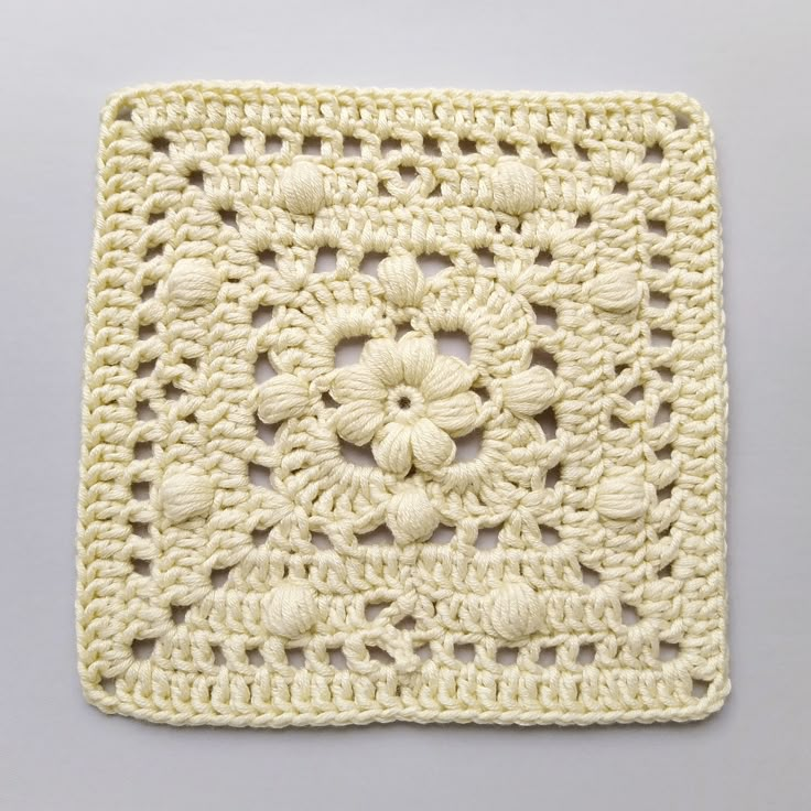 a crocheted square with white flowers on it