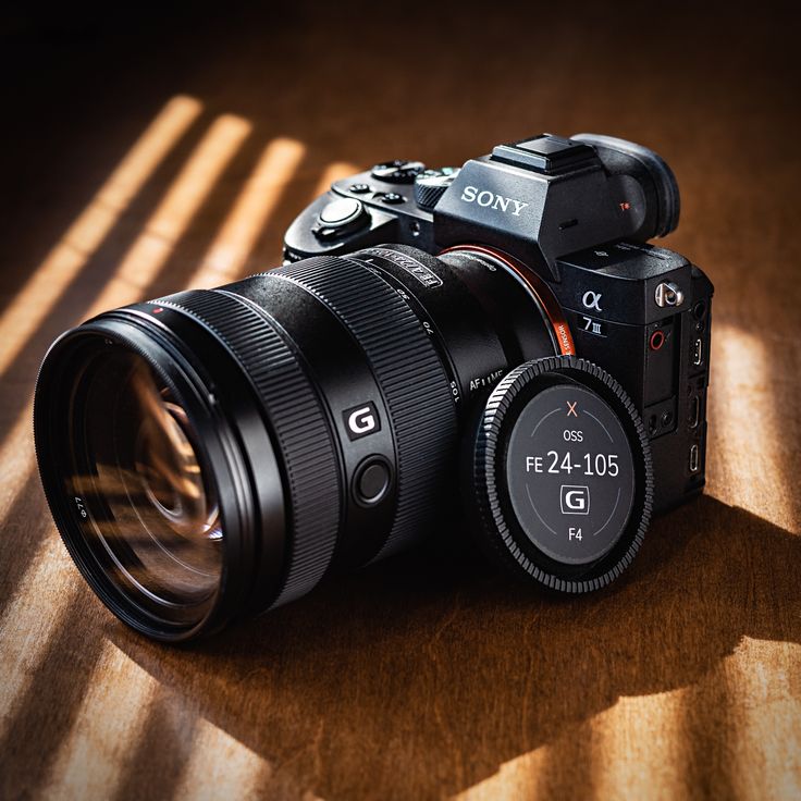 a sony camera sitting on top of a wooden table next to a window with the lens up