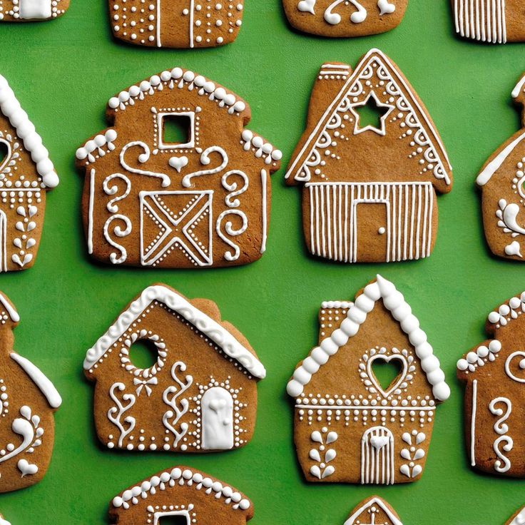 ginger cookies decorated with white icing are arranged on a green tablecloth in the shape of houses