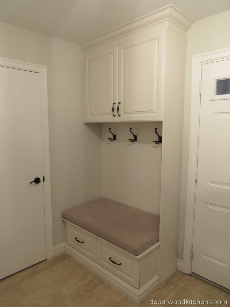 a room with white cabinets and a bench