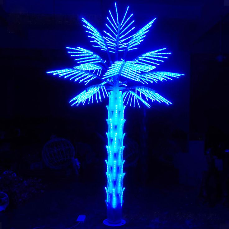 a lighted palm tree in the dark with blue lights on it's top and bottom