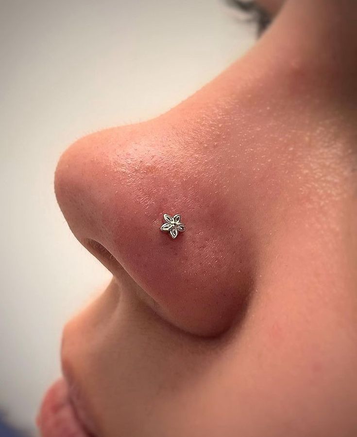 a close up of a person's nose with a tiny flower on it,