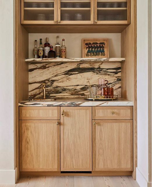 a kitchen with wooden cabinets and marble counter tops on the wall, along with an open cabinet door