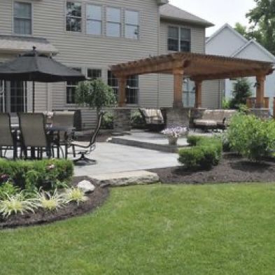 an outdoor patio with chairs and umbrellas in the grass next to a large house