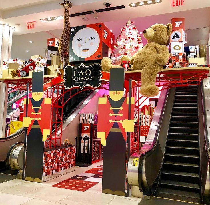 a teddy bear sitting on top of an escalator next to a christmas display