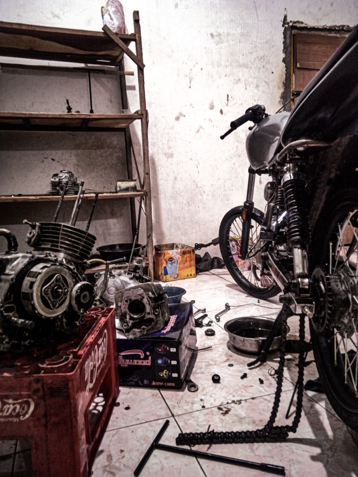 a motorcycle is being worked on in a garage with other parts scattered around the room