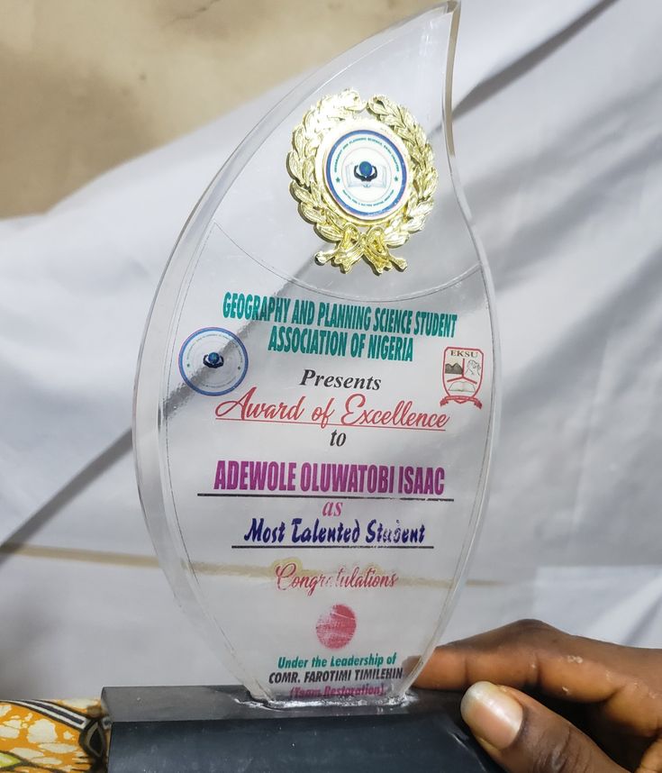 a person holding an award in front of a white sheet covered backdrop with the words excellence on it