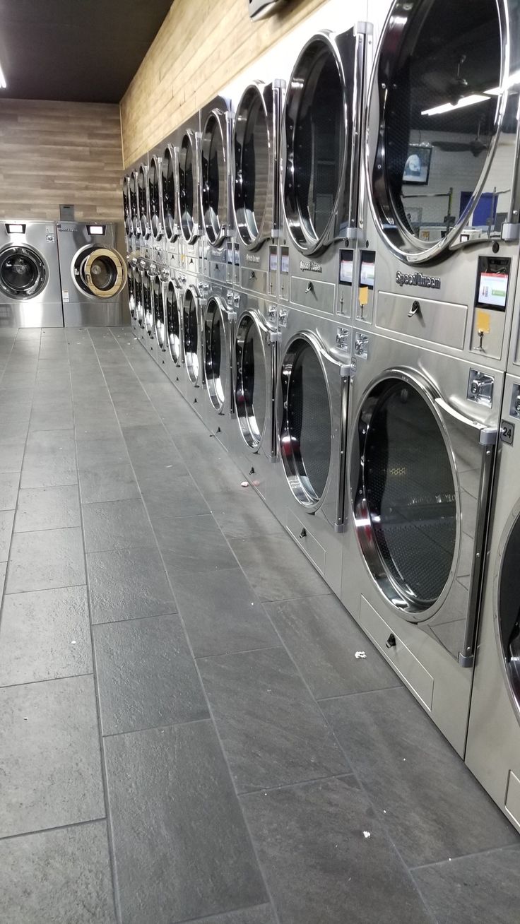 a long row of washers in a public laundment with tiled flooring