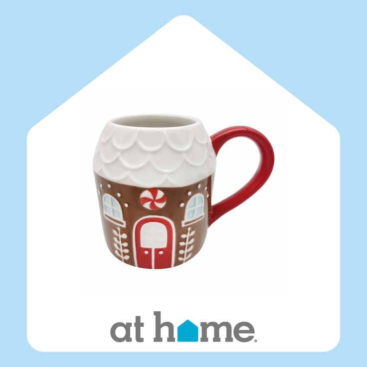 a red and white coffee mug with a gingerbread house design on it's side