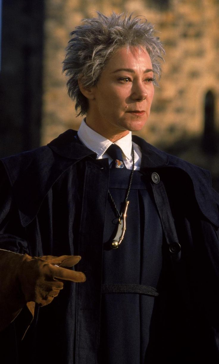 an older woman with grey hair wearing a black robe and holding her hands out to the side