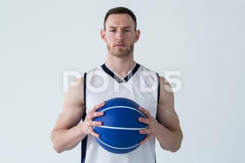 a basketball player holding a blue ball in his hands and looking up at the camera