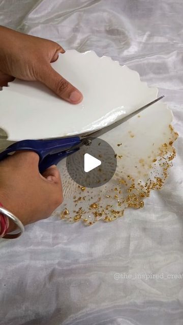 someone using scissors to cut paper with gold flakes on the bottom part of it