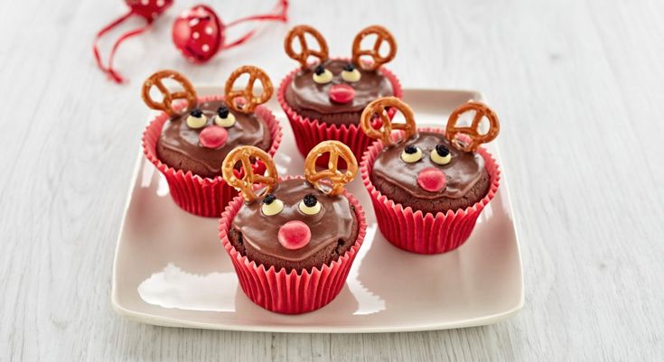 chocolate cupcakes decorated with reindeer noses and pretzels on a white plate