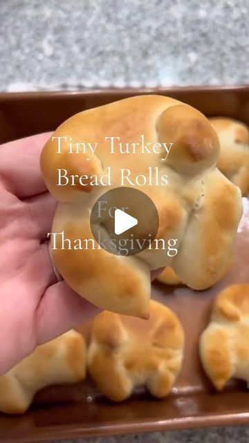 tiny turkey bread rolls are being held by someone's hand in a brown tray