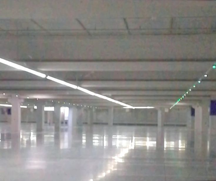 an empty parking garage filled with lots of white flooring and lights on the ceiling