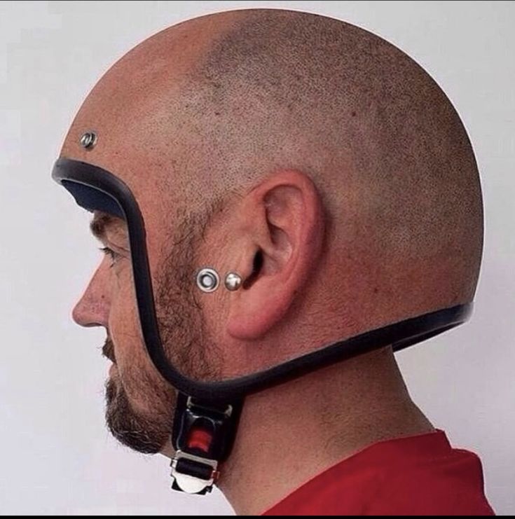 a bald man wearing a helmet with piercings on it's ears and nose