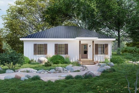 a small white house sitting on top of a lush green field