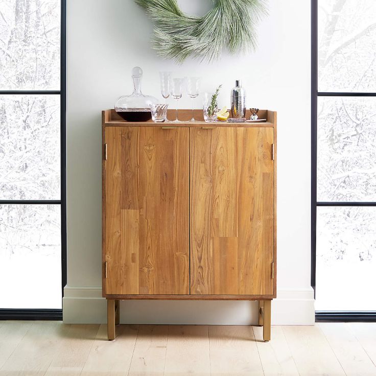 a wooden cabinet sitting in front of a window with a wreath on top of it