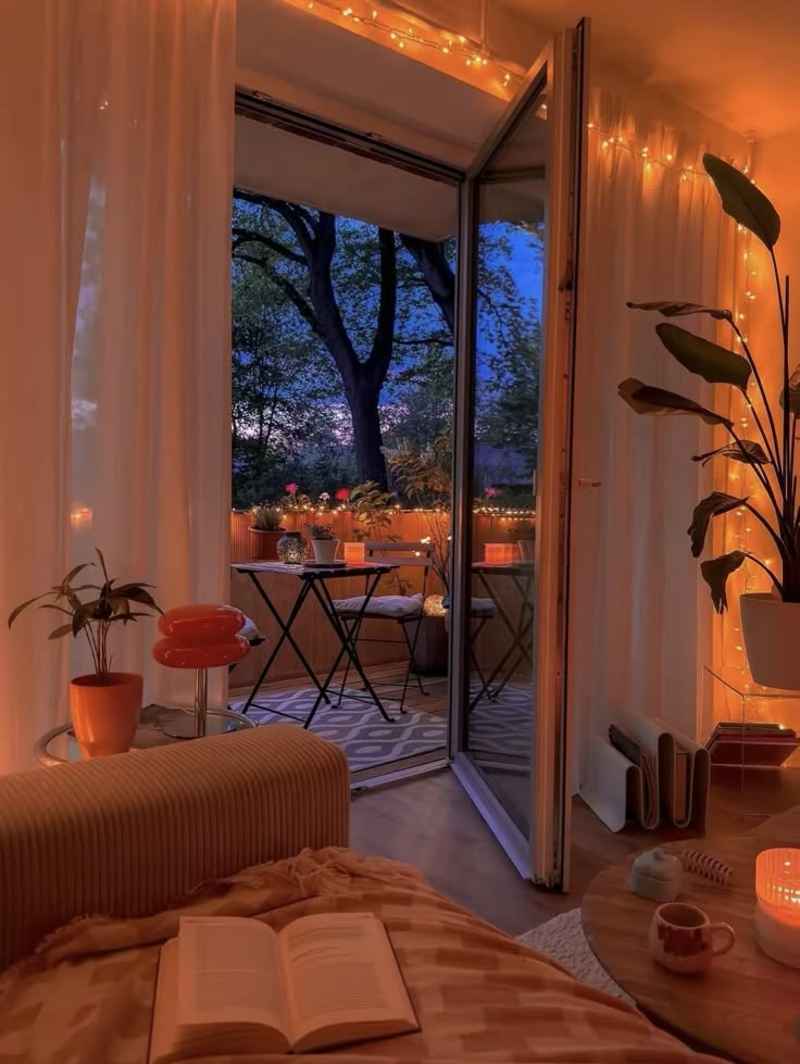 a living room filled with furniture next to a window covered in curtains and string lights