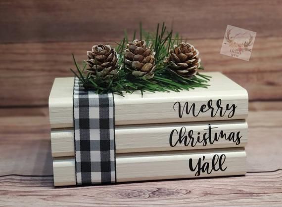 three wooden christmas books with pine cones on top