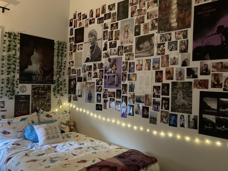 a bed with lots of pictures on the wall above it and lights strung from the headboard