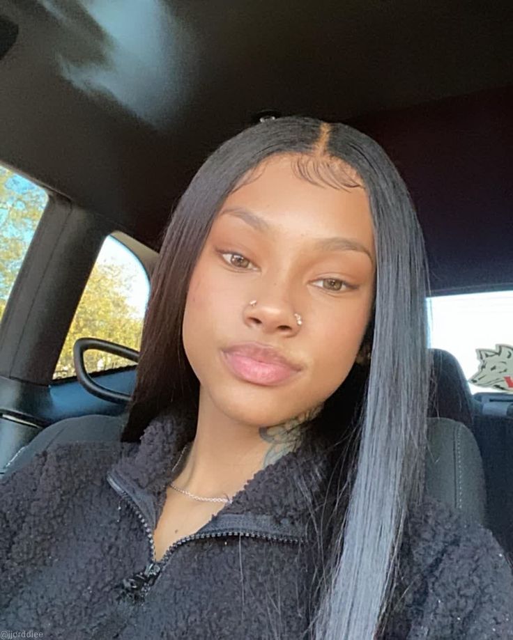 a woman sitting in the back seat of a car with her hair tied up to one side