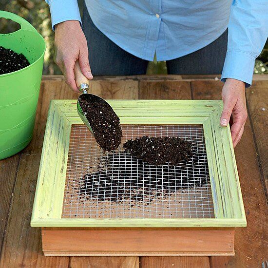 a person scooping dirt into a green container