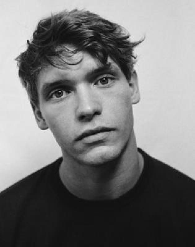 black and white photograph of a young man with short hair wearing a t - shirt