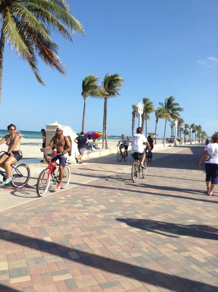 several people riding bikes on the beach with palm trees