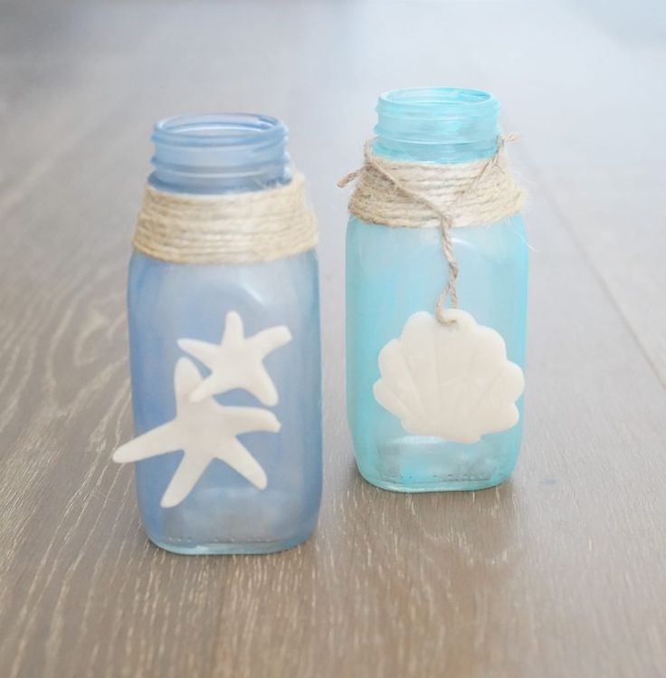 two glass jars sitting on top of a wooden table next to each other, one blue and one white