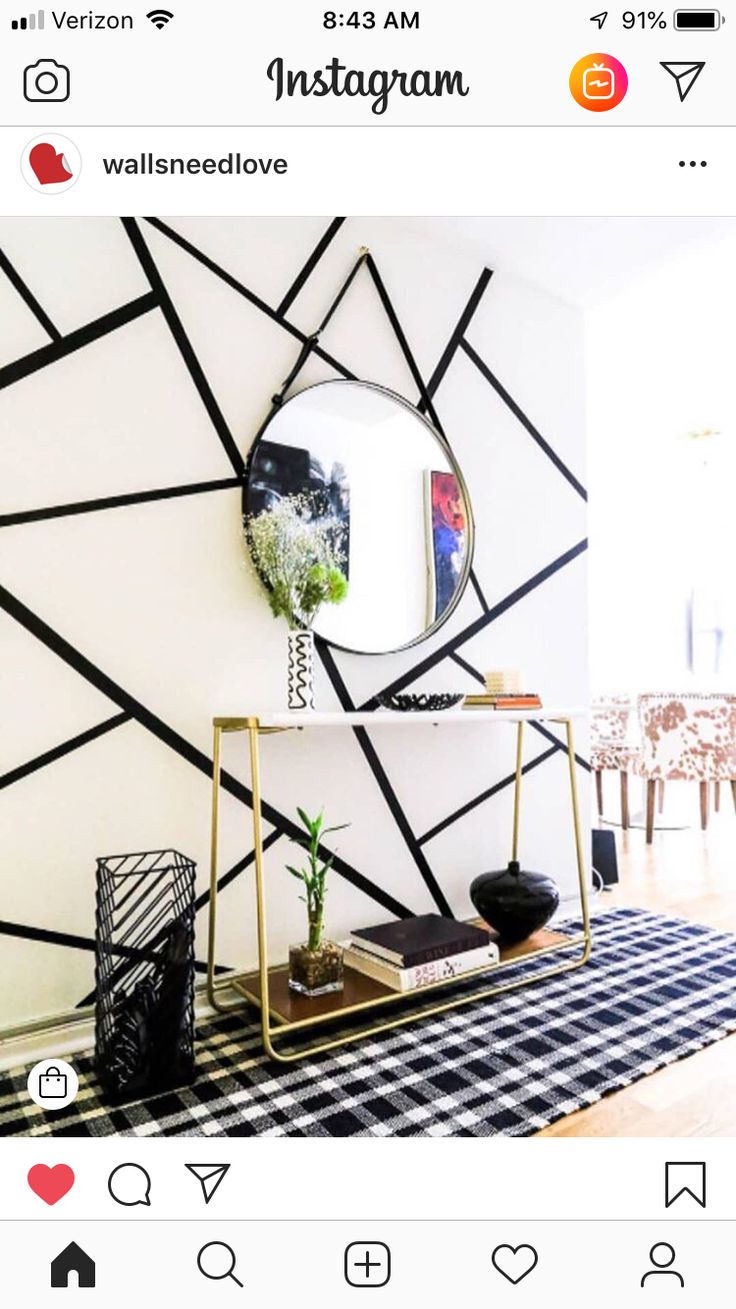 an instagram photo with a black and white geometric wallpaper, gold frame mirror and potted plant