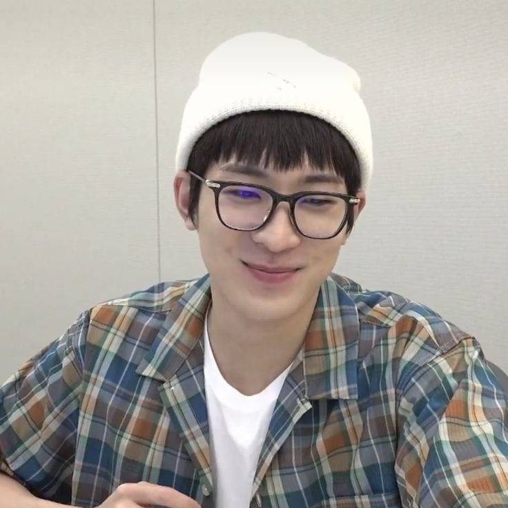 a young man wearing glasses and a white hat